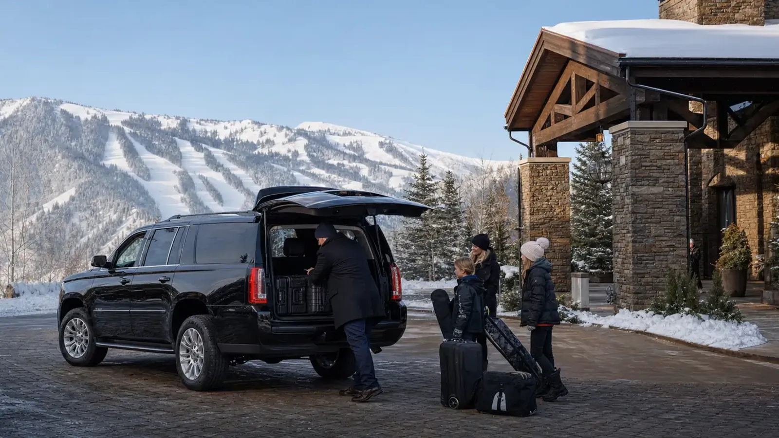 Private black SUV unloading a family at a snowy Deer Valley mountain resort